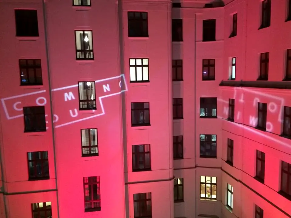Napis Coming Out wyświetlony na fasadzie dziedzińca podświetlonej na czerwono